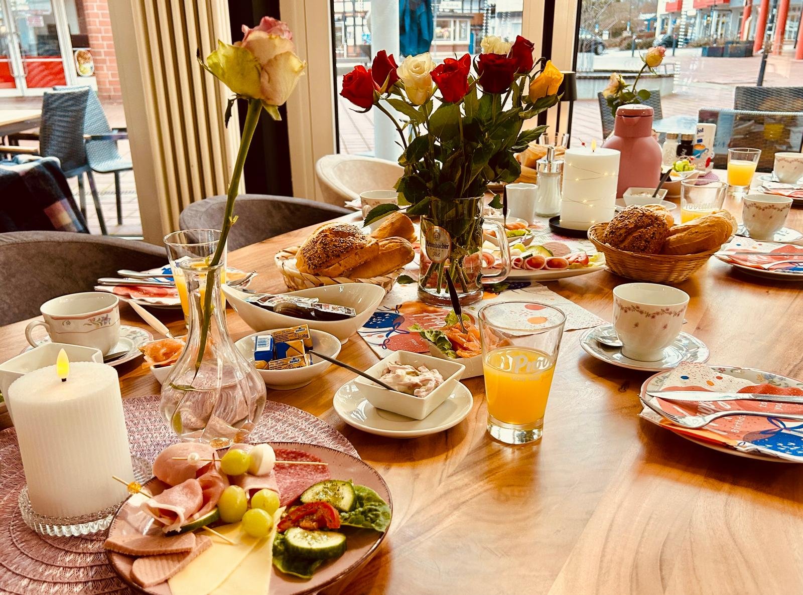 Reich gedeckter Frühstückstisch mit Brötchen, Käse und Obst